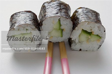 Three maki sushi with cucumber and chopsticks