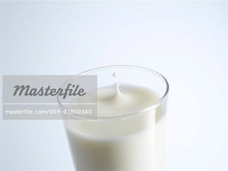 A glass of milk with a drop of milk