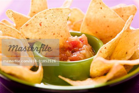 Tortilla chip dipped in tomato salsa