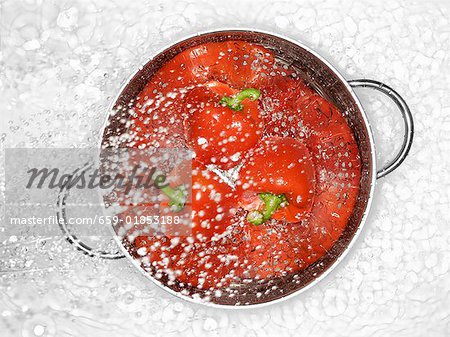 Peppers in a colander being sprayed with water