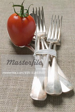 Une tomate avec fourchettes et cuillers