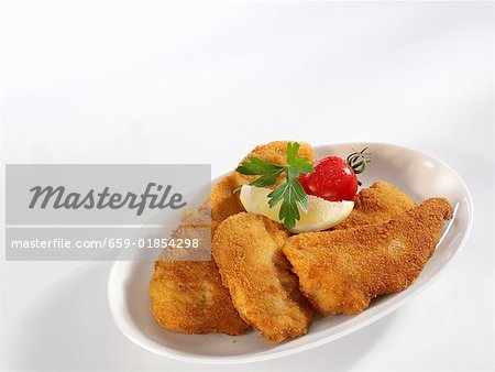 Trois Wiener Schnitzels (escalopes de veau) sur un plat de service