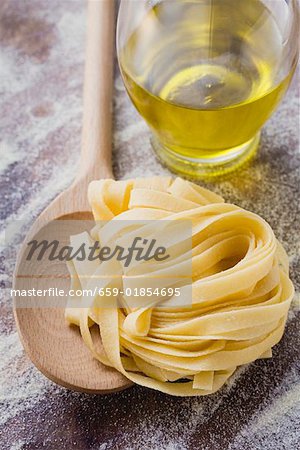 Home-made ribbon pasta with wooden spoon and olive oil