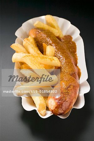 Currywurst with chips in paper dish