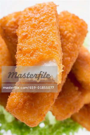 Fish finger with a bite taken on a heap of fish fingers