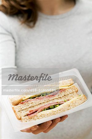 Femme tenant deux salami & fromage sandwichs en emballage