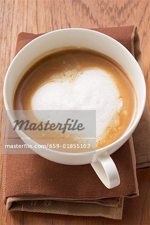 A cup of cappuccino with heart- shaped milk froth