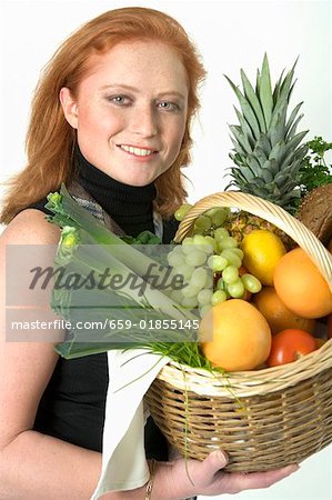 Young woman holding a basket of fruit and vegetables