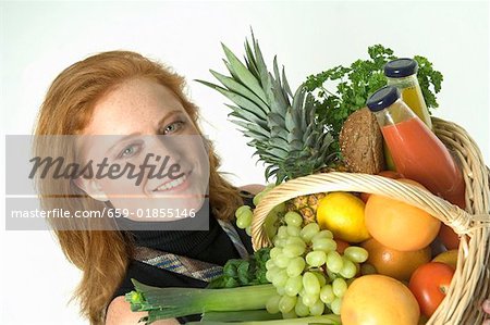 Young woman holding shopping basket full of fresh food