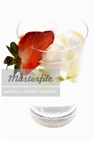 Mineral water with lime wedges, ice cubes and strawberry