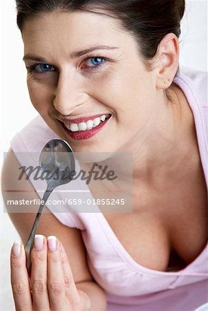 Frau lecken von einem Löffel Joghurt
