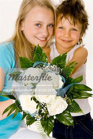 Boy and girl holding bouquet of white roses