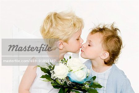 Zwei Kinder küssen über einen Strauß weiße Rosen