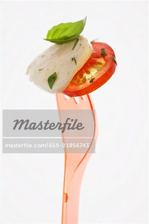 Tomaten mit Mozzarella und Basilikum auf Kunststoff-Gabel