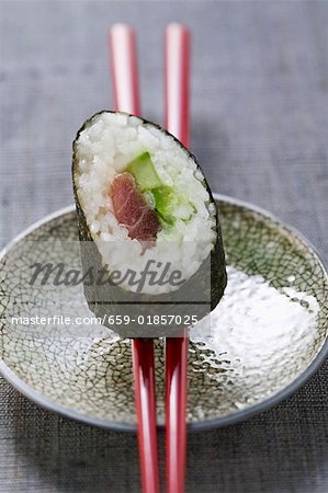 A maki sushi with tuna and cucumber on chopsticks