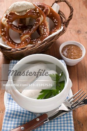 Two cooked Weisswurst in soup cup pretzels, mustard