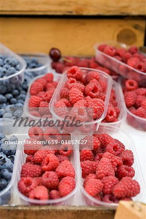 Raspberries and blueberries in plastic punnets at a market