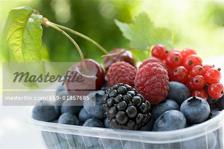 Assorted berries and two cherries in plastic punnet