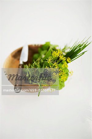 Assortiments d'herbes dans un bol en bois avec couteau Assortiments d'herbes dans un bol en bois avec couteau