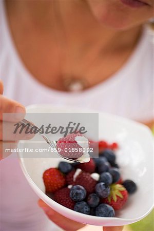 Woman eating berry muesli with yoghurt