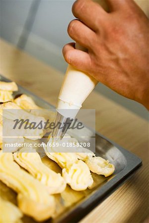 Crème de tuyauterie sur les éclairs avec une poche à douille