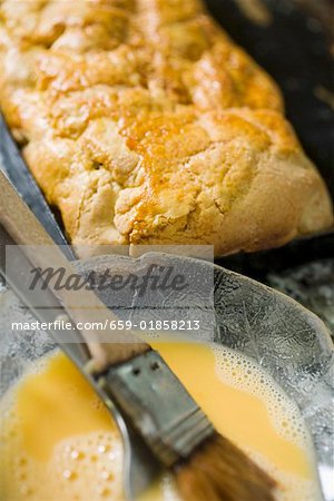 Au four strudel et oeuf jaune de œuf avec un pinceau à pâtisserie et la fourche