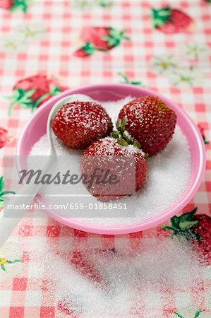 Trois fraises dans un petit plat de sucre