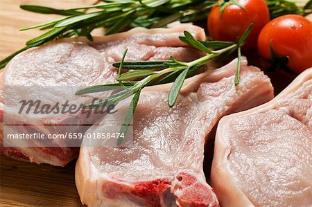 Raw pork chops with rosemary and tomatoes
