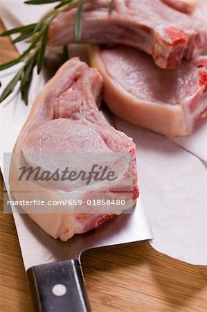 Raw pork chops with meat cleaver and rosemary