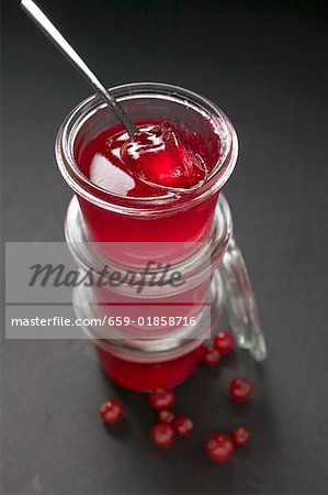 Three jars of redcurrant jelly, one opened, with spoon