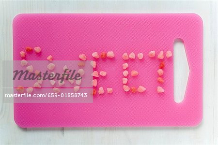 The word 'Sweet' written in sweets on pink chopping board
