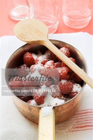 Gezuckerte Himbeeren in eine Pfanne, leere Marmeladengläser