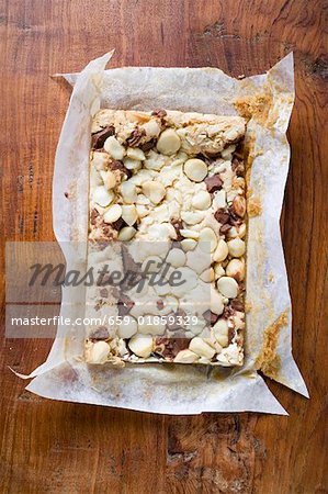 Chocolate slice with macadamia nuts in baking parchment