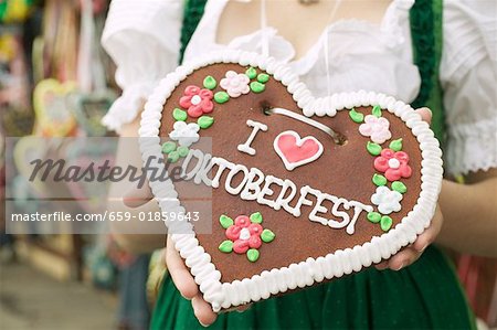 Woman in national dress holding Lebkuchen heart at Oktoberfest