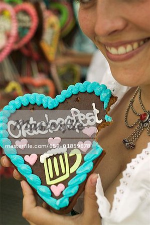 Woman holding Lebkuchen heart, a bite taken, at Oktoberfest