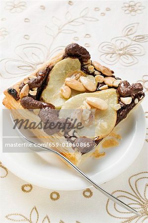 Piece of pear and chocolate tart with almonds on plate