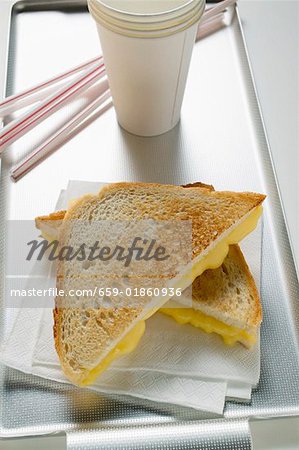 Toasted cheese sandwiches on paper napkin, paper cup, straws