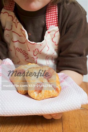 Child holding freshly baked puff pastries on cloth