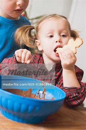 Girl eating Christmas biscuit with chocolate icing