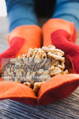 Hands in mittens holding walnuts