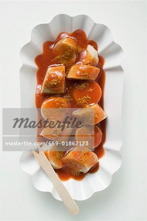 Bratwurst mit Ketchup & Currypulver in Papier Schale (overhead)