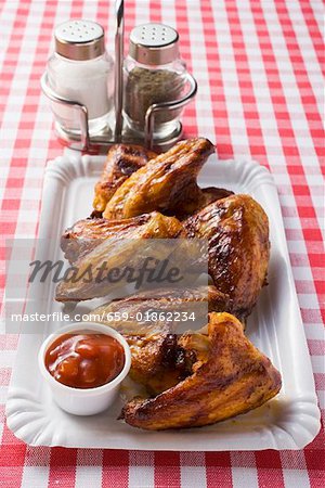 Grilled chicken wings with ketchup on paper plate