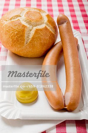 Frankfurters with mustard and bread roll on paper plate