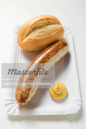 Sausage with mustard and baguette roll on paper plate