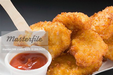 Hühner-Nuggets mit Ketchup in Papier-Schale