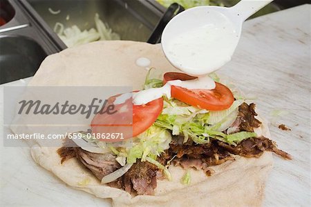 Making a döner wrap (sprinkling with yoghurt)