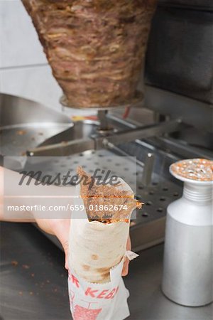 Hand holding döner wrap in a snack bar Hand holding döner wrap in a snack bar