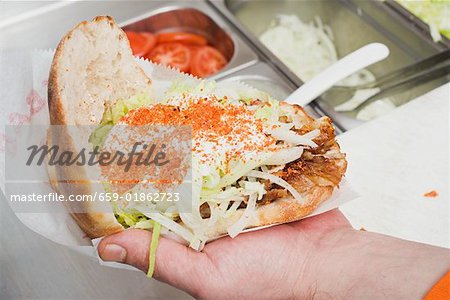 Hand holding a döner kebab (opened)