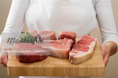 Person, die Rindfleisch-Steaks & Schweinefilet auf Schneidebrett