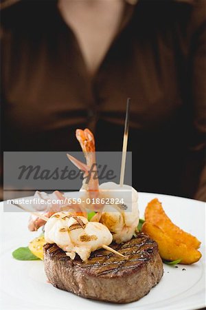 Woman holding plate of Surf & Turf (beef steak with prawns)